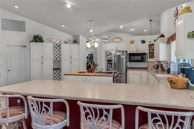 kitchen with visible vents, black microwave, lofted ceiling, stainless steel fridge, and a sink