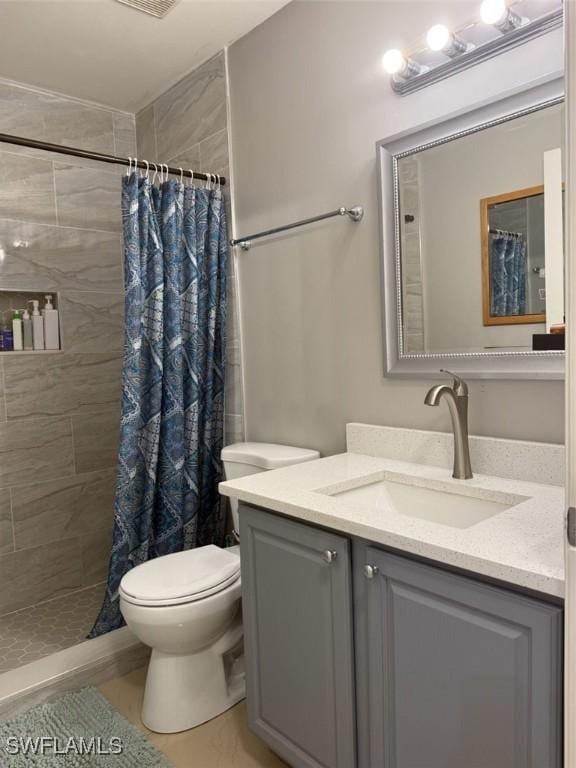 full bath featuring toilet, tiled shower, and vanity