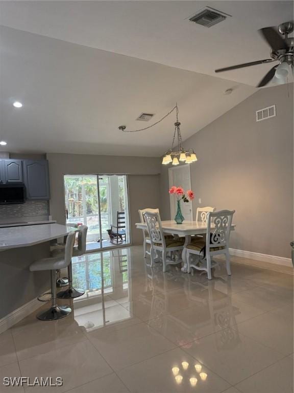 dining area with baseboards, visible vents, and vaulted ceiling