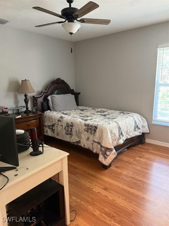 bedroom featuring a ceiling fan, baseboards, light wood finished floors, and visible vents