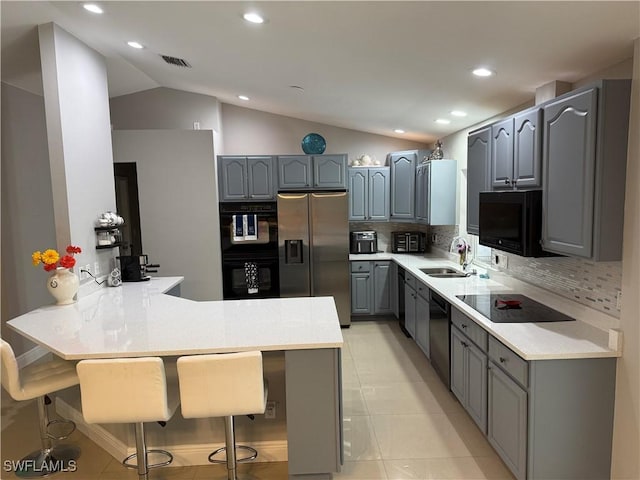 kitchen featuring gray cabinetry, black appliances, a sink, and a peninsula