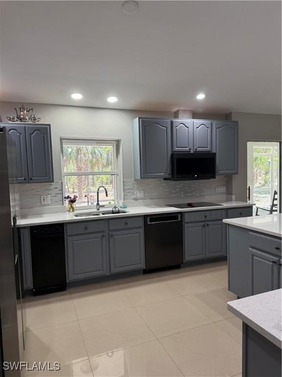 kitchen featuring gray cabinetry, black appliances, a sink, and a wealth of natural light