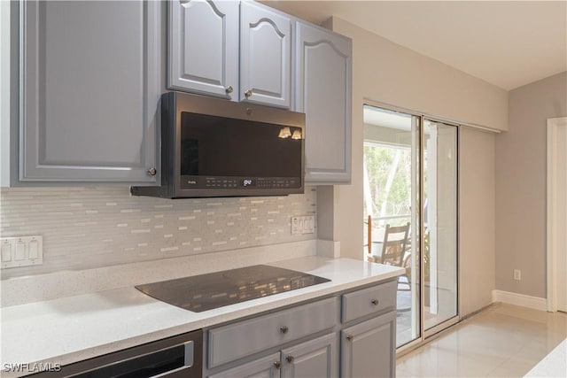 420 20th Ave NW, Naples, FL 34120 - kitchen featuring stainless steel microwave, black electric stovetop, gray cabinets, and tasteful backsplash