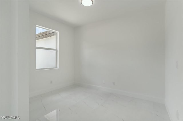 empty room featuring marble finish floor and baseboards