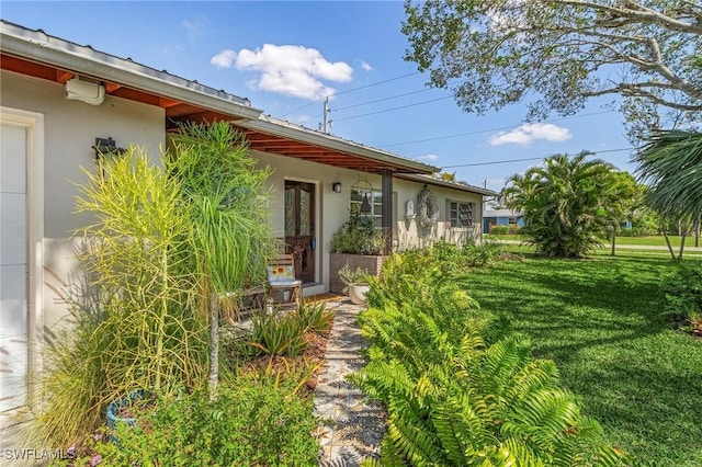 exterior space with stucco siding and a yard