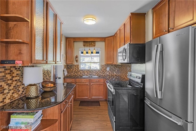 kitchen featuring brown cabinetry, a sink, stainless steel appliances, and open shelves