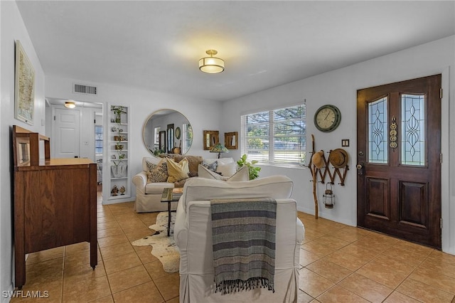 living area with light tile patterned floors, visible vents, and built in features