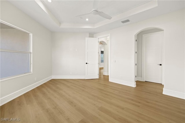 4831 Conover Ct, Fort Myers, FL 33908 - spare room featuring visible vents, a ceiling fan, arched walkways, light wood-style floors, and a tray ceiling