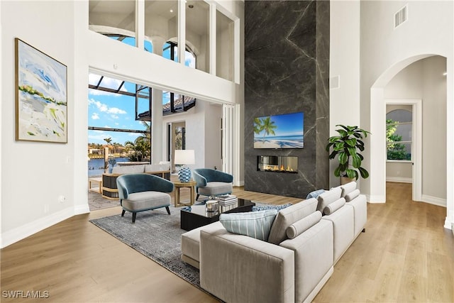 4831 Conover Ct, Fort Myers, FL 33908 - living room with a premium fireplace, a high ceiling, arched walkways, visible vents, and wood finished floors