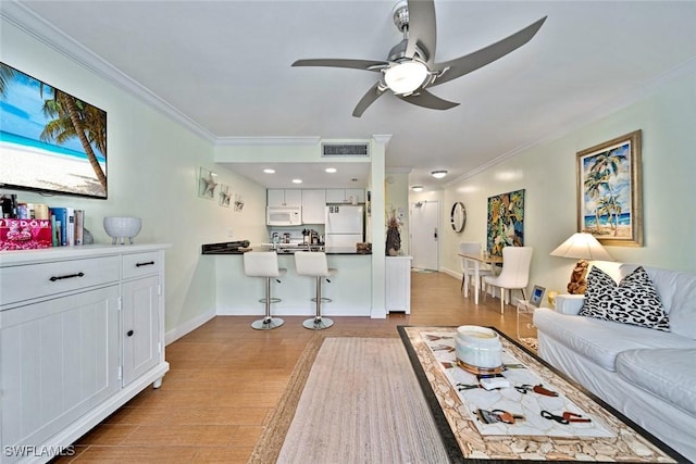 living area with ornamental molding, a ceiling fan, visible vents, and light wood-type flooring