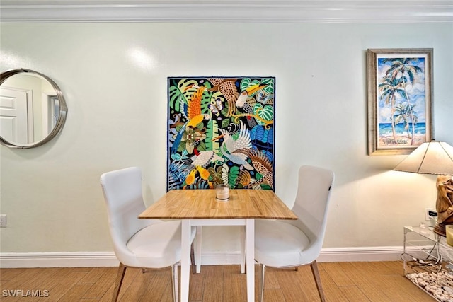 dining area featuring crown molding, wood finished floors, and baseboards