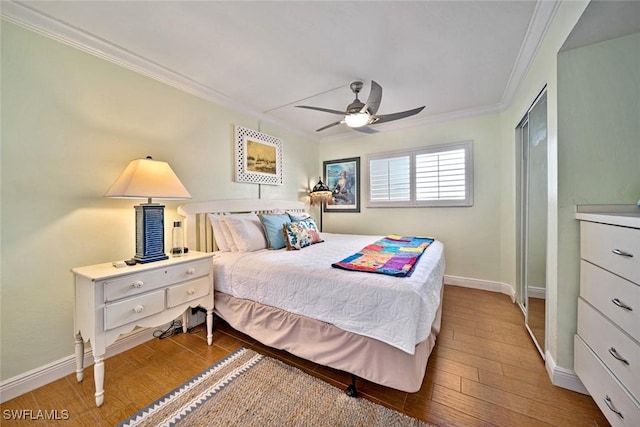 bedroom with ornamental molding, ceiling fan, baseboards, and wood finished floors