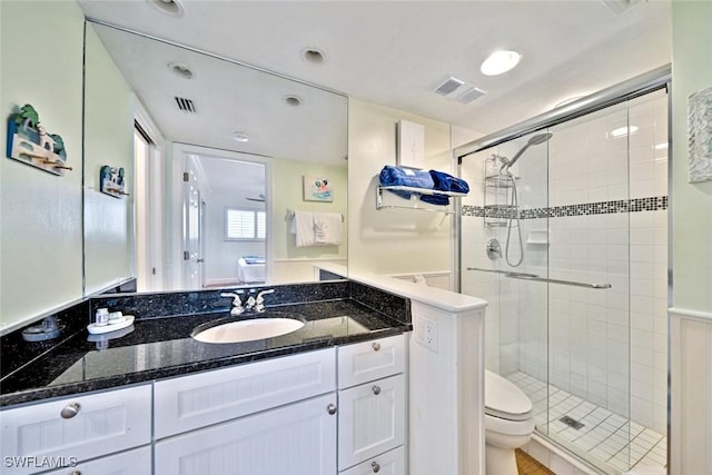 bathroom featuring vanity, toilet, visible vents, and a stall shower