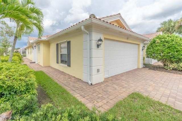 7639 Novara Ct, Naples, FL 34114 - view of side of home featuring a tile roof, driveway, stucco siding, and an attached garage