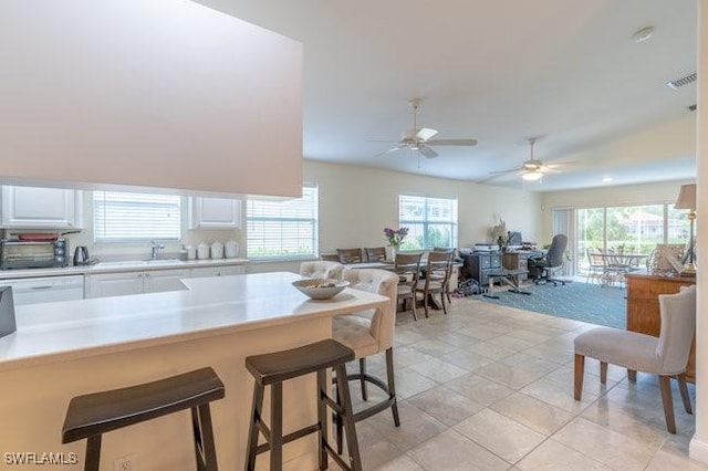 7639 Novara Ct, Naples, FL 34114 - kitchen with light countertops, a ceiling fan, a kitchen breakfast bar, visible vents, and white cabinets