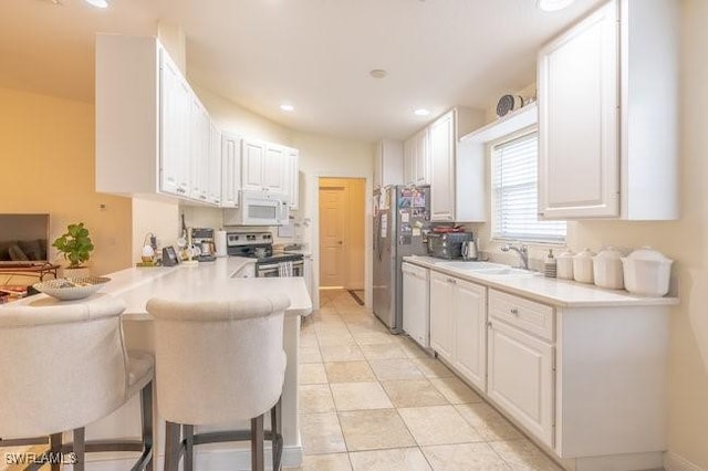 7639 Novara Ct, Naples, FL 34114 - kitchen with a sink, white cabinetry, a kitchen bar, appliances with stainless steel finishes, and a peninsula