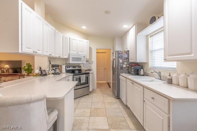 7639 Novara Ct, Naples, FL 34114 - kitchen featuring light countertops, a peninsula, appliances with stainless steel finishes, white cabinetry, and a sink