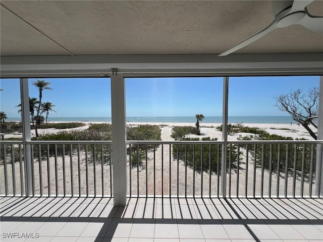 sunroom featuring plenty of natural light, a view of the beach, and a water view