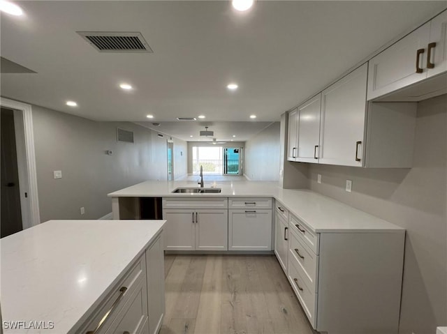 kitchen with light countertops, light wood-type flooring, visible vents, and a sink