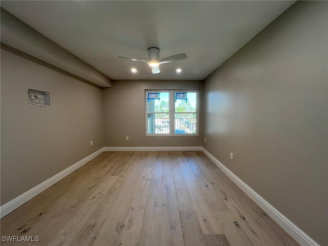 spare room with baseboards, light wood-style floors, and a ceiling fan