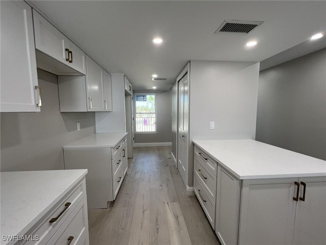 kitchen featuring light countertops, a peninsula, visible vents, and light wood-type flooring