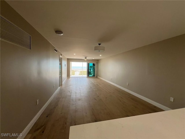 unfurnished living room featuring visible vents, baseboards, wood finished floors, and a ceiling fan