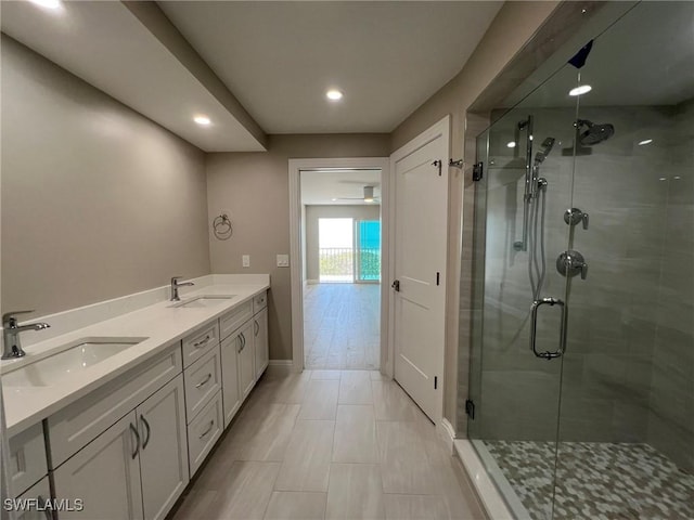 full bathroom featuring double vanity, a stall shower, baseboards, and a sink