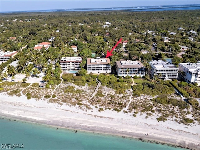 drone / aerial view with a forest view, a water view, and a view of the beach