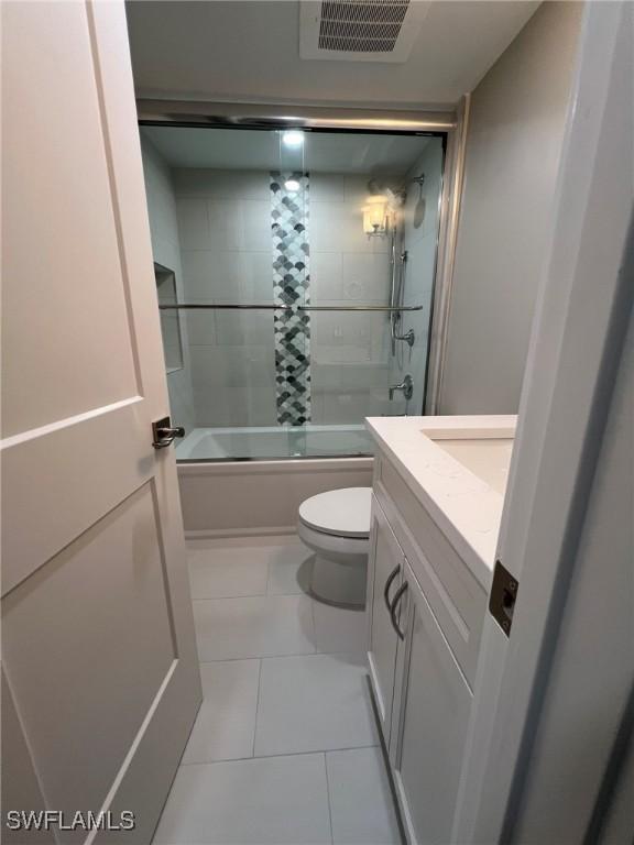 full bathroom featuring vanity, visible vents, shower / bath combination with glass door, tile patterned flooring, and toilet