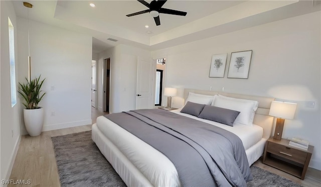 bedroom featuring ceiling fan, baseboards, recessed lighting, wood finished floors, and a raised ceiling