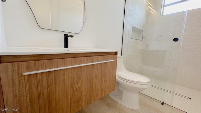 bathroom with vanity, toilet, and tiled shower