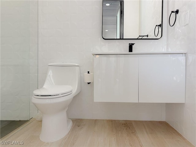 bathroom with toilet, tile walls, and vanity