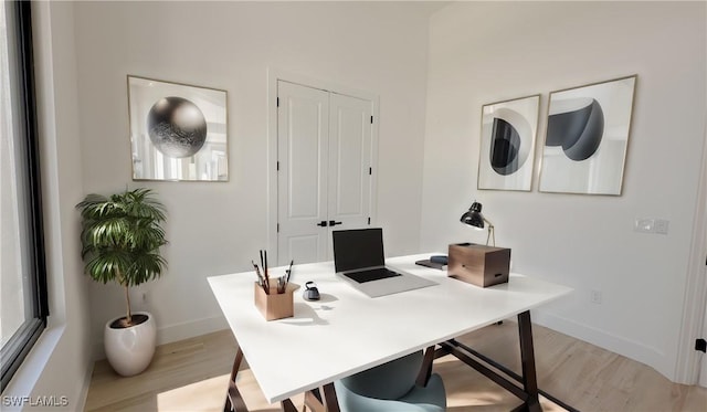 office space with baseboards and light wood-style flooring