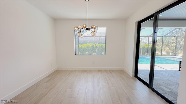 unfurnished room with light wood-style floors, baseboards, and a chandelier