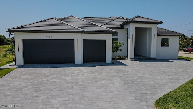 view of front of house featuring stucco siding, a tiled roof, an attached garage, and driveway