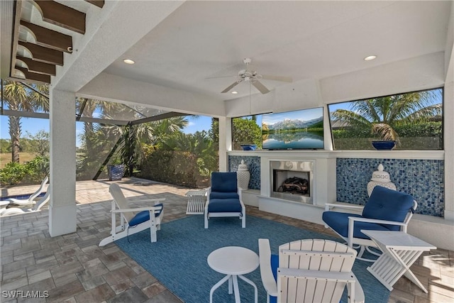 view of patio with a lanai, a ceiling fan, and an outdoor fireplace