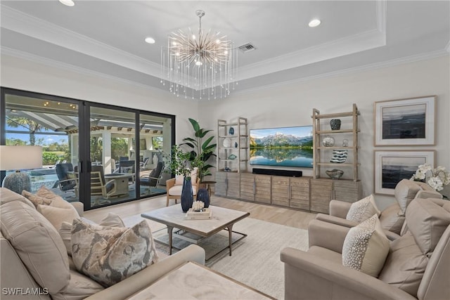 living room featuring visible vents, ornamental molding, a tray ceiling, wood finished floors, and an inviting chandelier