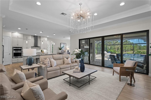 living area featuring visible vents, a raised ceiling, an inviting chandelier, and ornamental molding