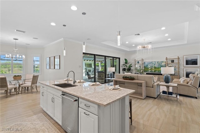 kitchen with a sink, stainless steel dishwasher, open floor plan, an inviting chandelier, and a raised ceiling