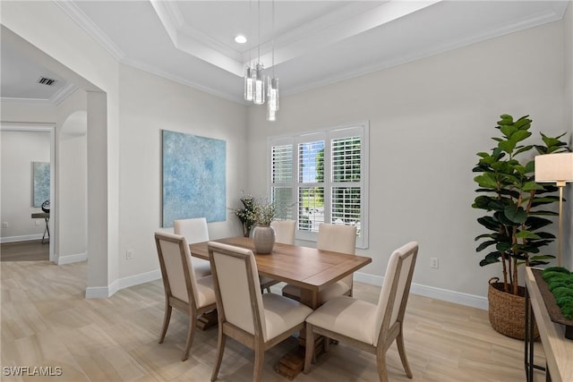 dining area with a notable chandelier, light wood-style flooring, ornamental molding, baseboards, and a raised ceiling