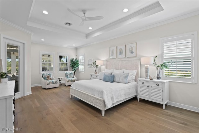 bedroom with visible vents, baseboards, a tray ceiling, ornamental molding, and wood finished floors