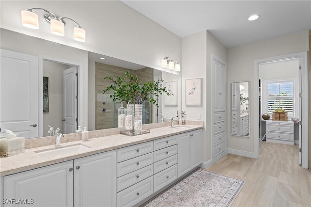 full bathroom with double vanity, recessed lighting, a tile shower, and a sink