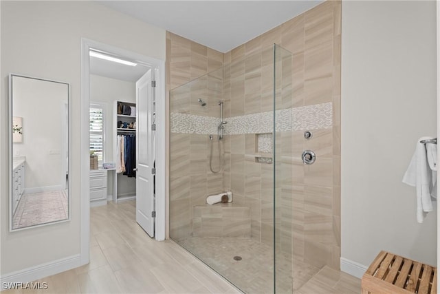 bathroom with a stall shower, a walk in closet, and baseboards