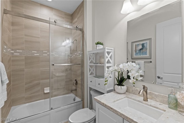 full bath with vanity, toilet, and bath / shower combo with glass door