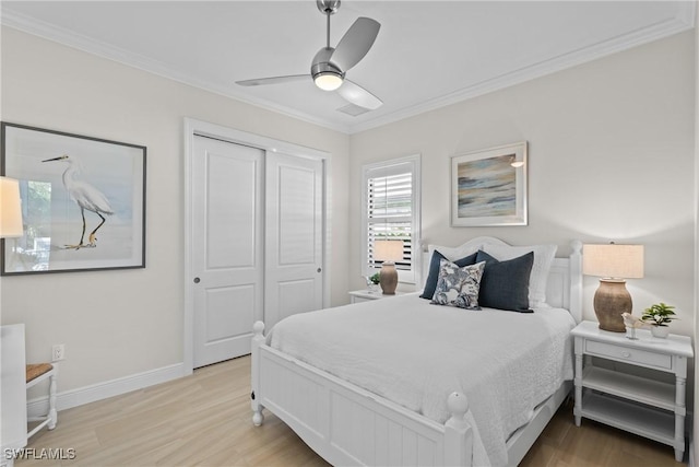 bedroom with baseboards, wood finished floors, a closet, and ornamental molding