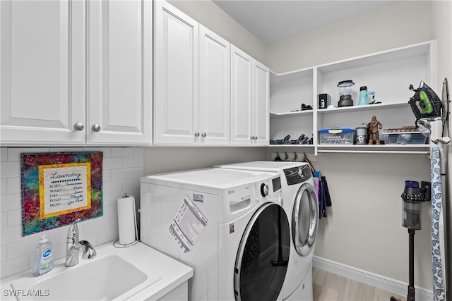 laundry room with washing machine and dryer, cabinet space, baseboards, and a sink