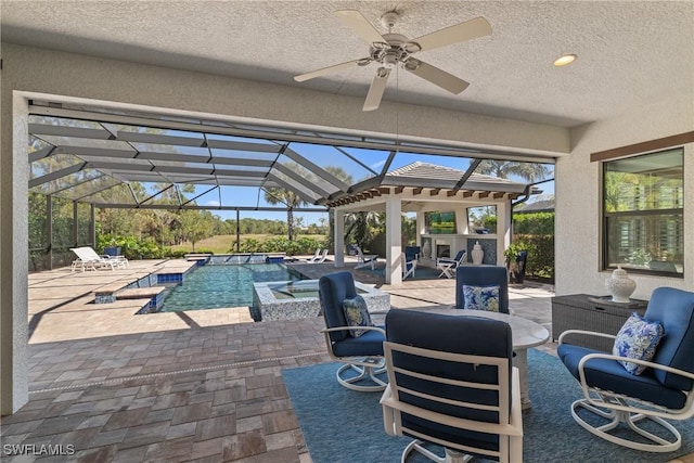 outdoor pool with glass enclosure, a ceiling fan, a patio area, and an outdoor hangout area