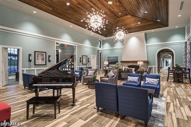 living area featuring a chandelier, a tray ceiling, wooden ceiling, arched walkways, and high vaulted ceiling