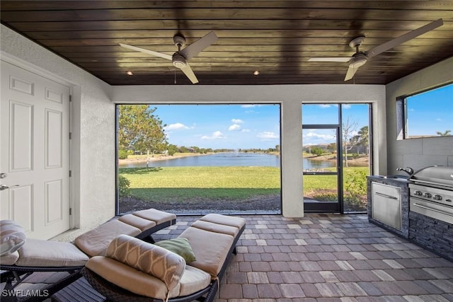 sunroom featuring wood ceiling, a ceiling fan, and a water view