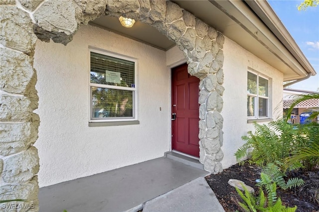 entrance to property with stone siding and stucco siding